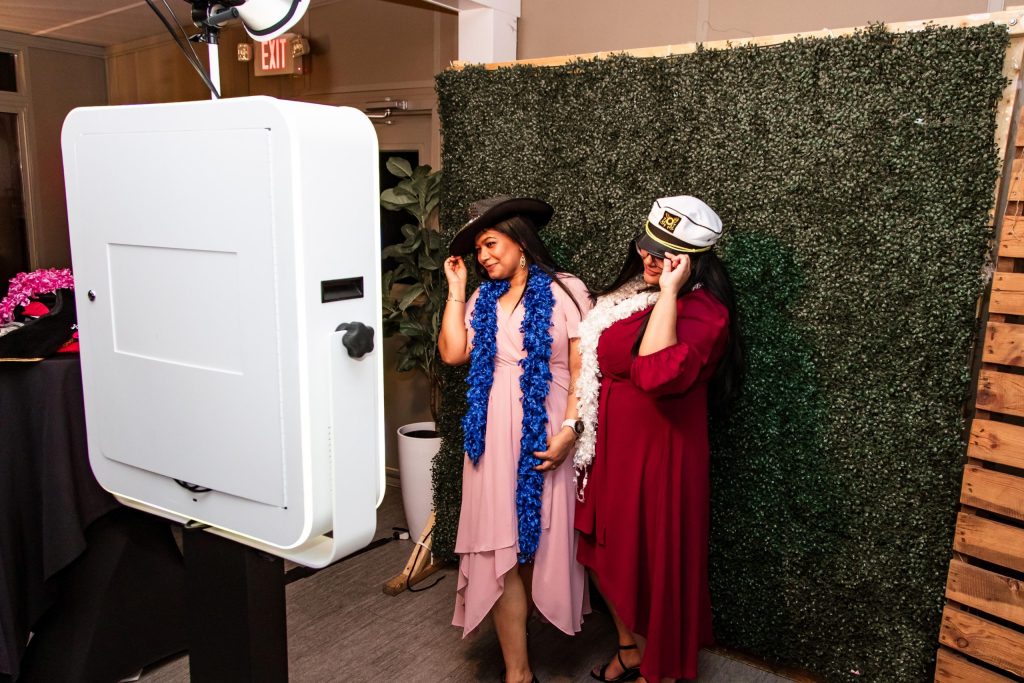 Guests laughing and posing with props in the In The Mix Event Group wedding photo booth, capturing fun memories during the reception.