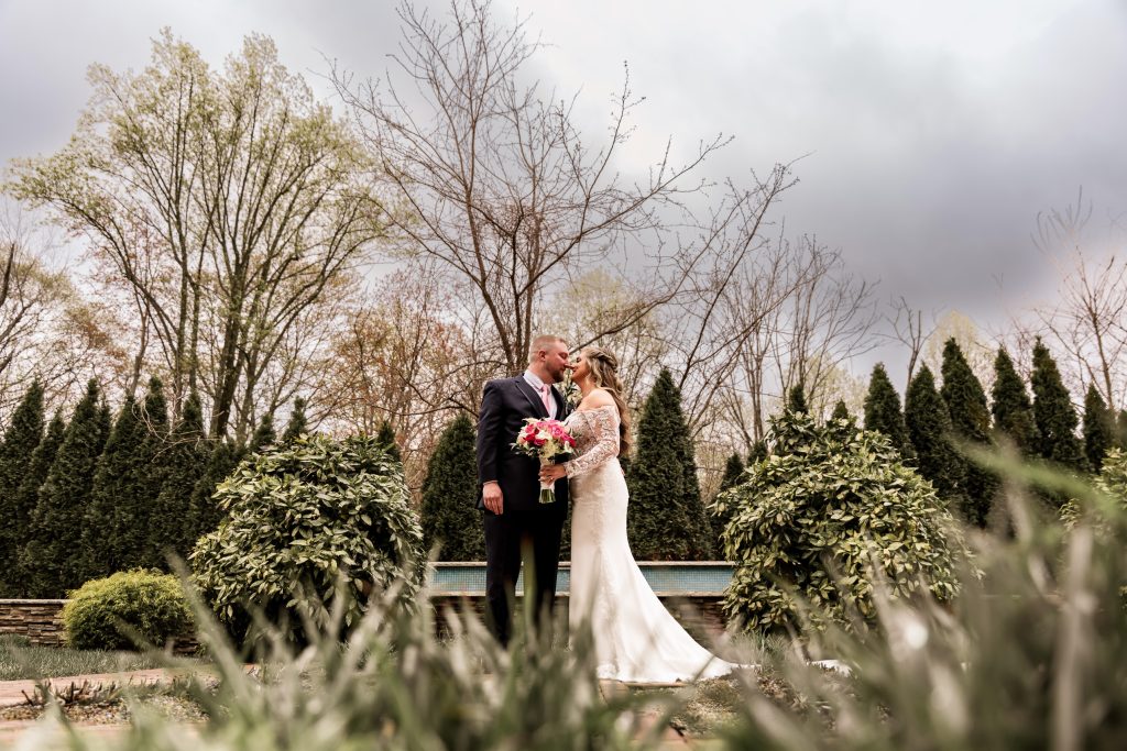 Bride and groom kissing in a garden captured by In The Mix Event Group wedding photography services.